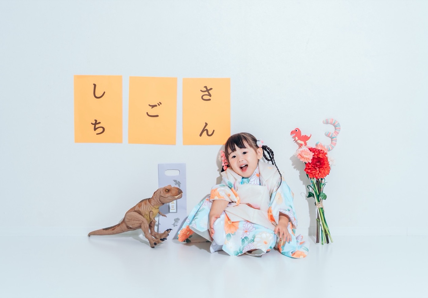七五三の記念写真|着物姿のお子さんのそばに、ダリア・ガーベラ・カーネーションの小さめの花束